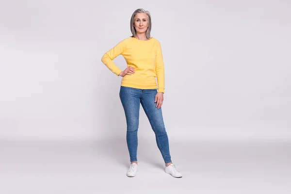 Pełny rozmiar zdjęcie szczęśliwy przystojny piękny babcia nosić żółty sweter i dżinsy izolowane na szarym tle kolor — Zdjęcie stockowe
