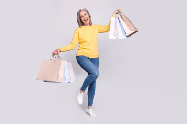 Full size photo of happy excited lovely grandmother shopaholic hold bags isolated on grey color background — Stok fotoğraf