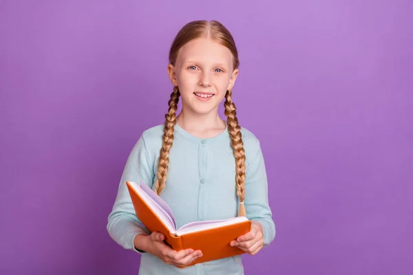 Foto von fröhlich positiven netten kleinen Mädchen halten Buch lesen glänzendes Lächeln tragen blaues Hemd isoliert violette Farbe Hintergrund — Stockfoto