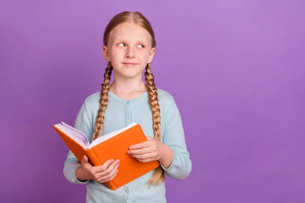 Foto von klugen nachdenklichen Mädchen halten gelesene Buch suchen leeren Raum merken tragen blaues Hemd isoliert violetten Hintergrund — Stockfoto