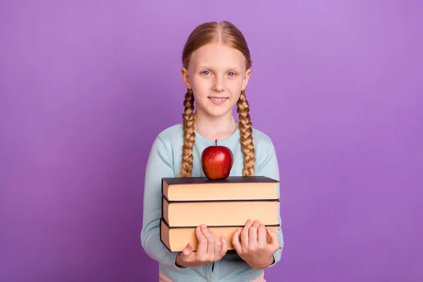 Photo of cheerful pupil girl hold book apple look camera beaming smile wear blue shirt isolated violet color background — Stock Photo, Image