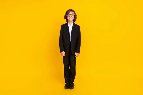 Foto des fröhlichen positiven Jungen strahlendes Lächeln tragen Brille schwarze Uniform isoliert gelbe Farbe Hintergrund — Stockfoto