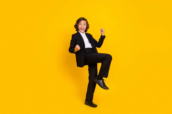 Photo of astonished crazy boy raise fists scream yeah wear black uniform isolated yellow color background — Stok fotoğraf