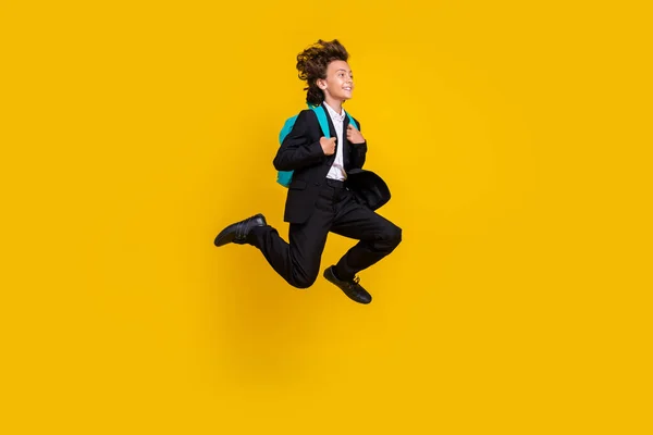Profile photo of carefree small boy jump run wear rucksack black uniform isolated yellow color background — Stockfoto