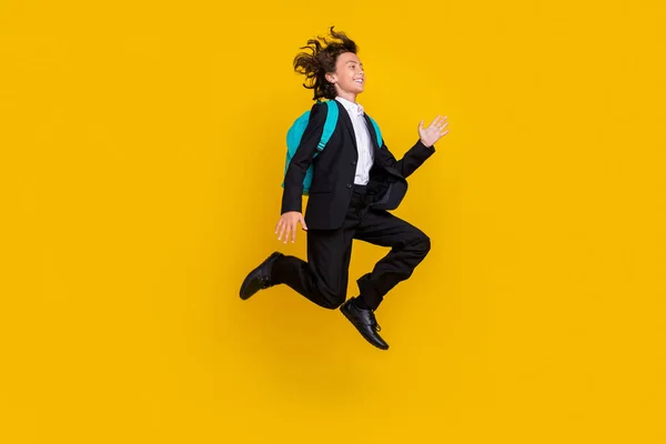 Profile photo of sportive crazy small boy jump hurry run wear bag black uniform isolated yellow color background — Stock Fotó