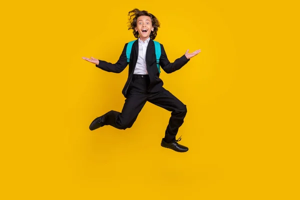 Photo of sporty energetic small boy jump excited mood wear bag black uniform isolated yellow color background — Stok fotoğraf