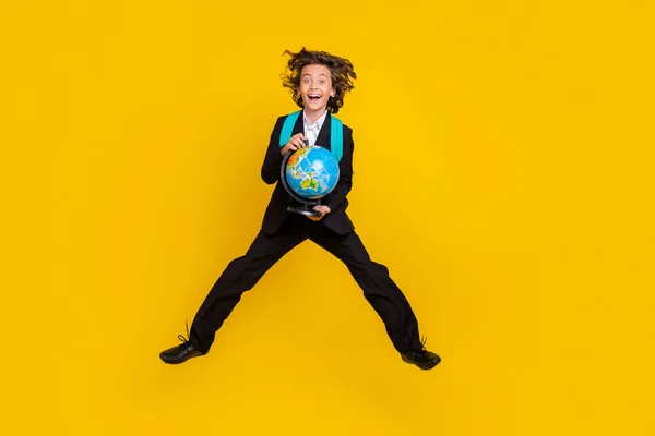 Photo of active schoolchild jump hold globe wear backpack black uniform isolated yellow color background — Foto Stock