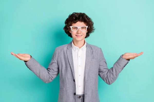 Photo of cute charming schoolboy dressed grey suit glasses showing scales compare arms empty space isolated teal color background — Stockfoto