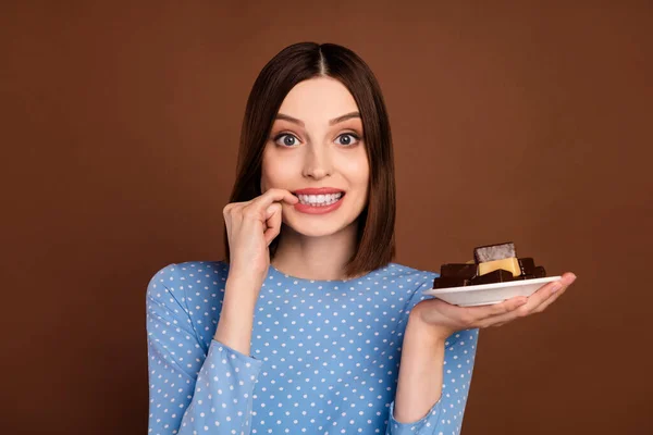 写真の若い女の子のかむ指の歯空腹の食事を保持キャンディプレート砂糖甘い茶色の色の背景に孤立 — ストック写真