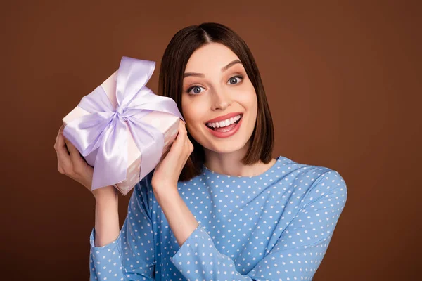 Foto de impressionado millennial morena senhora segurar presente desgaste camisa azul isolado no fundo de cor marrom — Fotografia de Stock