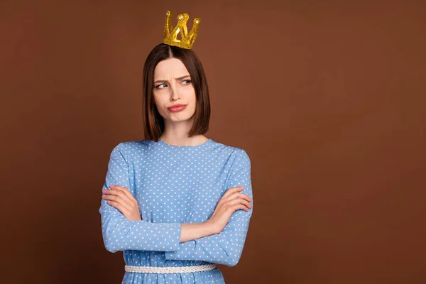 Foto de joven infeliz niña malhumorada manos dobladas desgaste princesa corona mirada espacio vacío aislado sobre fondo de color marrón —  Fotos de Stock