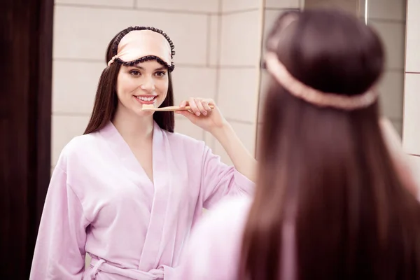 Foto af søde charmerende unge dame pink søvntøj ser spejl smilende børste tænder indendørs værelse hjem - Stock-foto