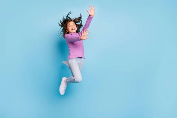 Фотография маленькой девочки в натуральную величину, выпрыгивающей в повседневной одежде на голубом фоне — стоковое фото