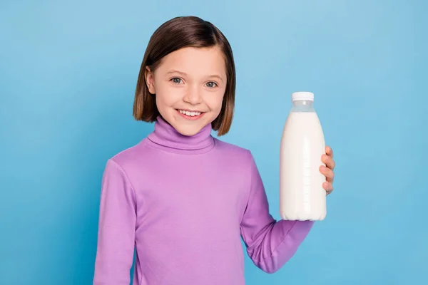 Foto retrato niña sonriendo manteniendo botella con leche aislada pastel color azul fondo — Foto de Stock