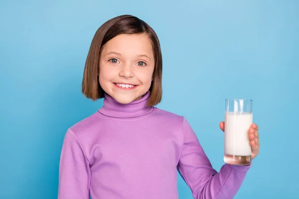 Bild av charmig söt liten skolflicka klädd violett polotröja dricka glas mjölk isolerad blå färg bakgrund — Stockfoto