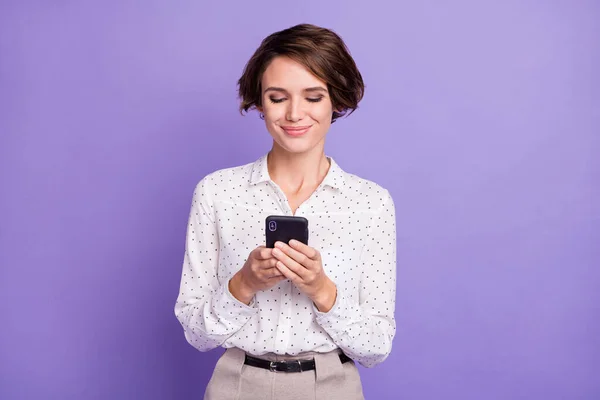 Portret van mooie brunette kort kapsel optimistische dame houden telefoon slijtage wit shirt geïsoleerd op lila kleur achtergrond — Stockfoto