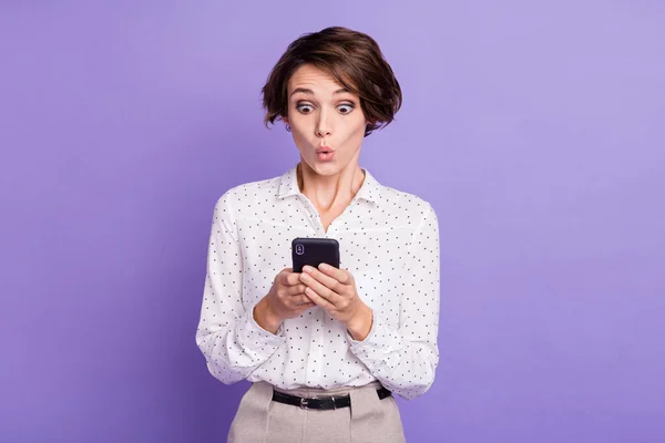 Portret van mooie brunette kort kapsel onder de indruk dame houden telefoon slijtage wit shirt geïsoleerd op lila kleur achtergrond — Stockfoto