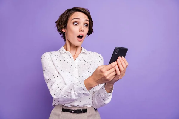 Portret van mooie brunette kort haar onder de indruk dame houden telefoon slijtage wit shirt geïsoleerd op lila kleur achtergrond — Stockfoto