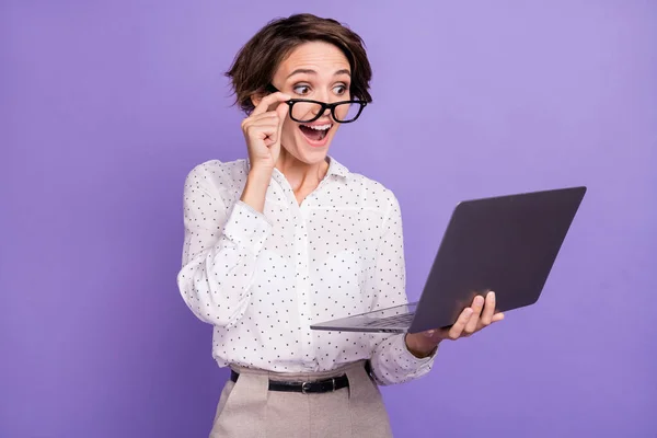Retrato de morena agradável cabelo curto impressionado senhora tipo laptop desgaste óculos camisa isolada no fundo cor lilás — Fotografia de Stock