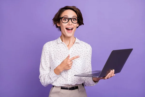 Retrato de bom morena cabelo curto impressionado senhora ponto laptop desgaste óculos camisa isolada no fundo cor lilás — Fotografia de Stock