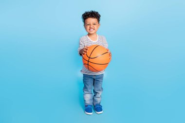 Full length body size view of nice cheerful boy playing basketball isolated over bright blue color background clipart