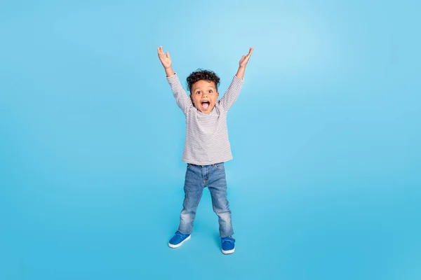 Plná délka tělo velikost pohled na atraktivní veselý chlapec stoupající ruce nahoru izolované přes jasně modré barvy pozadí — Stock fotografie