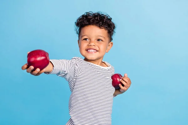 Retrato de atractivo niño alegre que le da la cuota de manzana fresca aislado sobre fondo de color azul vibrante —  Fotos de Stock