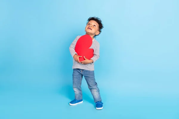 Plná délka velikosti těla pohled na atraktivní veselý snivý chlapec drží srdce izolované přes jasně modré barvy pozadí — Stock fotografie