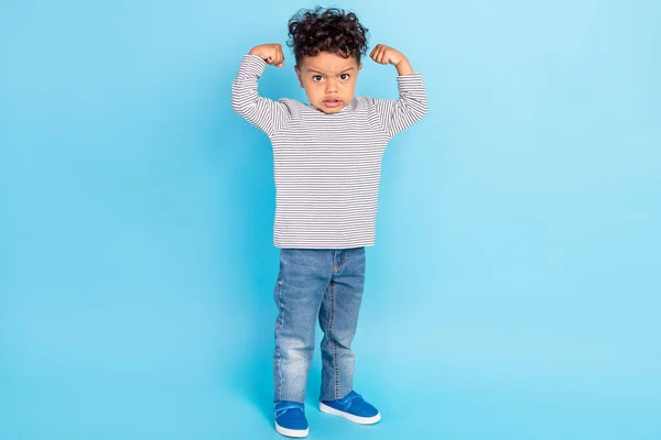 Повнометражний розмір тіла привабливого смішного сильного хлопчика, що демонструє м'язи ізольовані на яскраво-блакитному фоні — стокове фото
