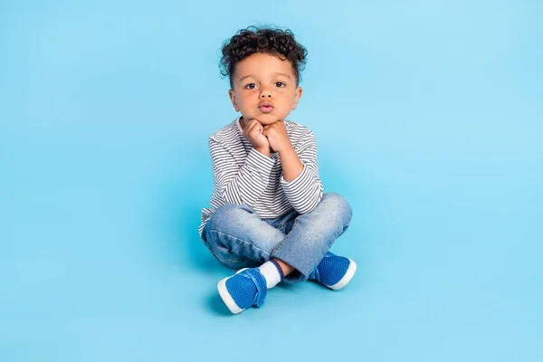 Retrato de chico enfocado atractivo sentado en el suelo pose de loto mirando aislado sobre fondo de color azul brillante — Foto de Stock