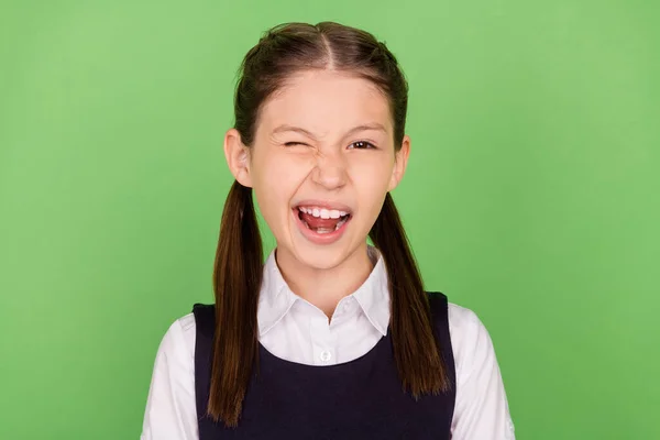 Foto de doce engraçado menina da escola vestida roupas formais piscando sorrindo isolado fundo cor verde — Fotografia de Stock