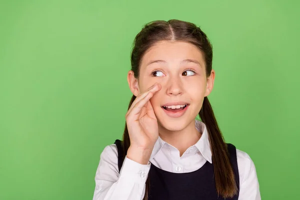 Photo of young school girl happy positive smile hand near mouth speak gossip look empty speak isolated over green color background — Stock Photo, Image