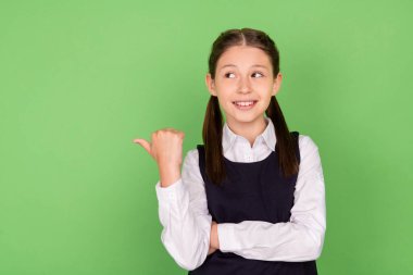 Photo of young school girl happy positive smile point thumb empty space ad promo choose isolated over green color background clipart