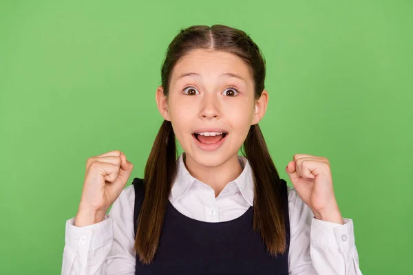 Foto retrato menina sorrindo vestindo uniforme gestos como vencedor isolado pastel cor verde fundo — Fotografia de Stock