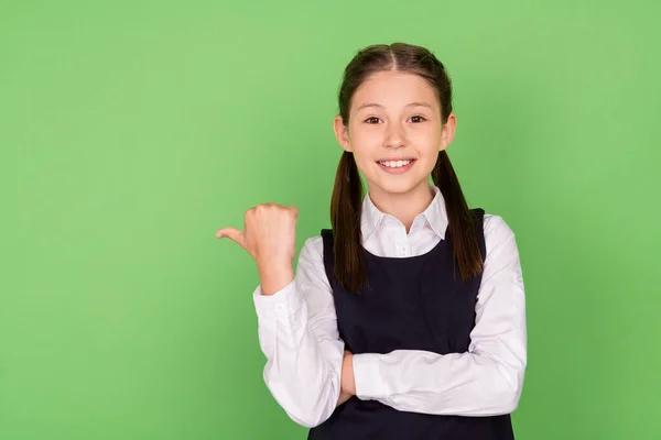 Foto retrato menina sorrindo mostrando espaço em branco com polegar isolado pastel cor verde fundo — Fotografia de Stock