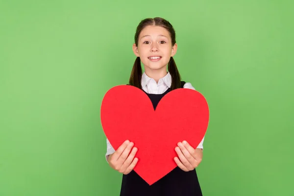 Foto retrato menina bonito alegre mantendo vermelho papel coração cartão postal isolado pastel cor verde fundo — Fotografia de Stock