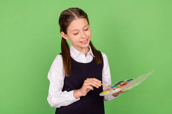 Φωτογραφία πορτρέτο μαθήτρια κρατώντας παλέτα χρωμάτων με πινέλο χρώματος απομονωμένο παστέλ πράσινο χρώμα φόντο — Φωτογραφία Αρχείου