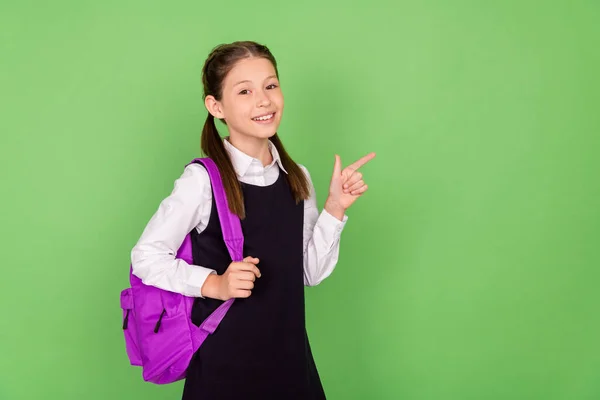 Fényképezés portré iskolás lány hátizsák mutatja copyspace ujj elszigetelt pasztell zöld színű háttér — Stock Fotó