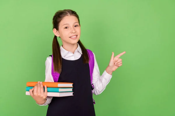 Foto portret schoolmeisje met rugzak boek stapel tonen lege ruimte geïsoleerde pastel groene kleur achtergrond — Stockfoto