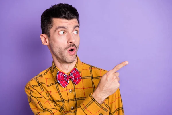 Genç adamın fotoğrafı şaşkın şaşkın bak işaret parmağı boş alan mor renk arkaplan üzerinde izole bir reklam göstermektedir — Stok fotoğraf