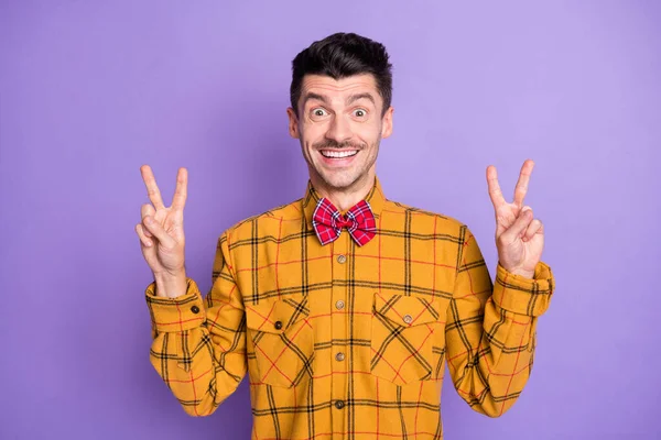 Photo de sourire excité jeune homme habillé chemise à carreaux montrant v-signes deux mains bras isolé couleur pourpre fond — Photo
