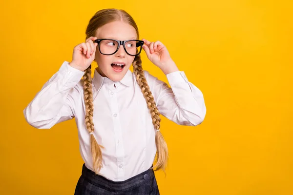 Foto von fröhlichen Schüler berühren Brille suchen interessiert leeren Raum isoliert auf gelbem Hintergrund — Stockfoto