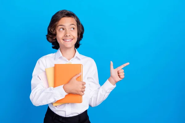 Fotografie legrační vysněný školní chlapec nosit formální oblečení s úsměvem ukazující prázdný prostor izolované modré barvy pozadí — Stock fotografie