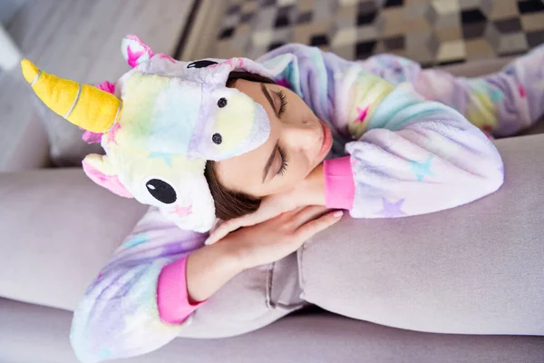 Foto von schläfrig verträumt entspannt süße Dame schlafen haben Mittagsschlaf sitzen Couch tragen cosplay Einhorn kigurumi drinnen — Stockfoto