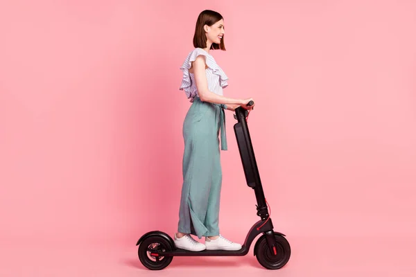 Full size profile side photo of young girl happy positive smile ride electric scooter isolated over pink color background — Stock Photo, Image