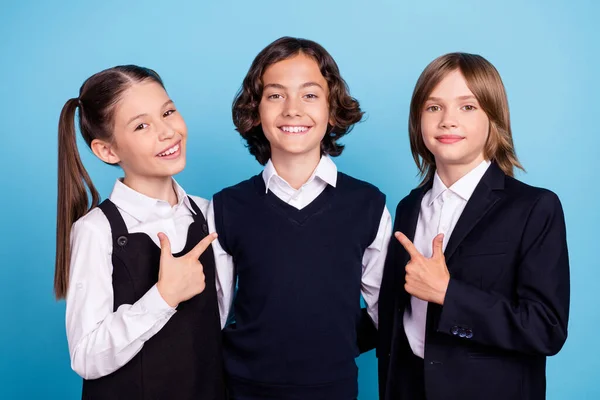 Foto de brillante fresco colegiales usan uniforme abrazo abrazo apuntando dedo ellos mismos aislado color azul fondo — Foto de Stock