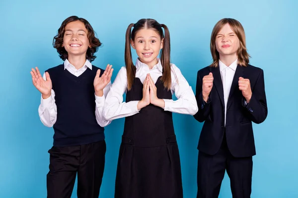 Foto de dulce rezando colegiales formalwear sonriendo pidiendo fines de semana vacaciones buenas notas aislado color azul fondo —  Fotos de Stock