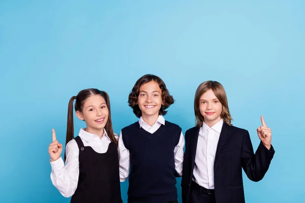 Photo portrait school mates smiling in uniform pointing finger up blank space isolated pastel blue color background — Stock Photo, Image