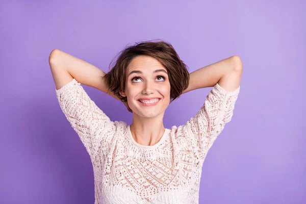 Photo de brillante adorable jeune femme habillée chemise blanche bras derrière la tête regardant vers le haut espace vide isolé fond de couleur violette — Photo