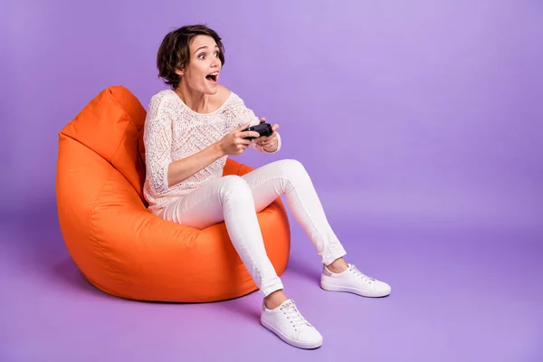 Photo of funny sweet woman nosić dzianiny siedzi fasola playstation patrząc puste miejsce odizolowane fioletowy kolor tła — Zdjęcie stockowe